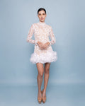Vestido Sammy mini de encaje bordado en tono blanco con cuello alto, manga larga y falda con volumen en tul y plumas blancas.
